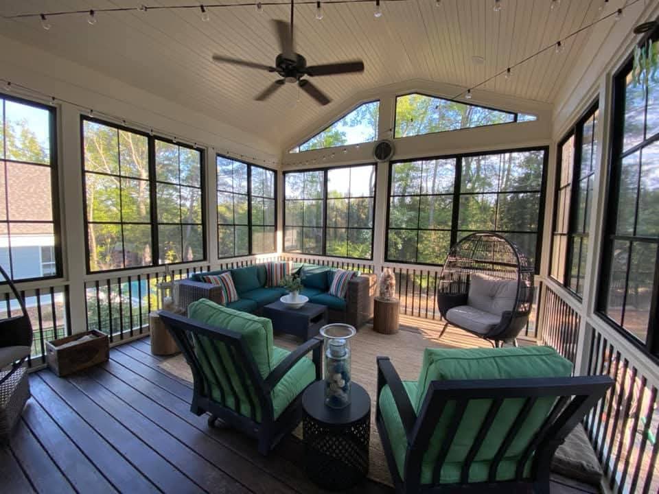 Inviting sunroom with green chairs, a hanging chair, and large windows for natural light.