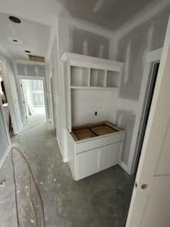 Modern hallway with unfinished drywall and a white cabinetry unit for laundry or storage.