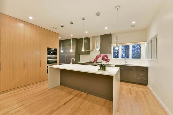 Modern kitchen with pendant lighting, wood cabinets, and a central island with orchids.