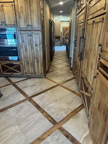 Rustic wooden cabinetry and tiled flooring in a spacious kitchen corridor.