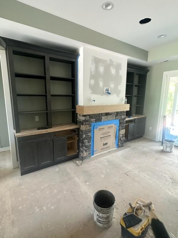 Modern living room with stone fireplace and dark wood built-in shelves under renovation.