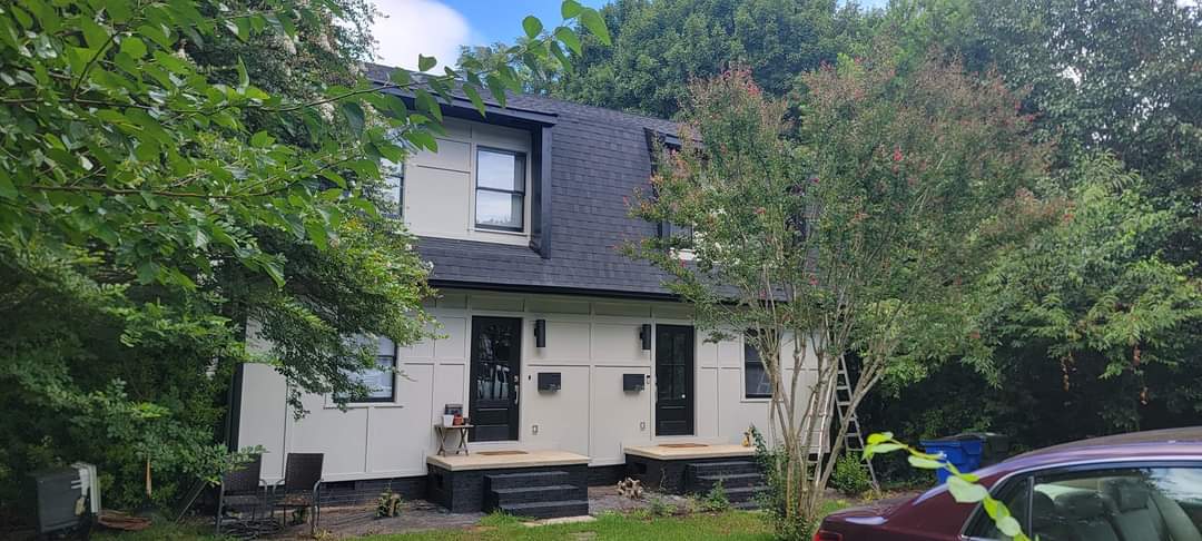Duplex home with modern design, front porches, and lush landscaping.