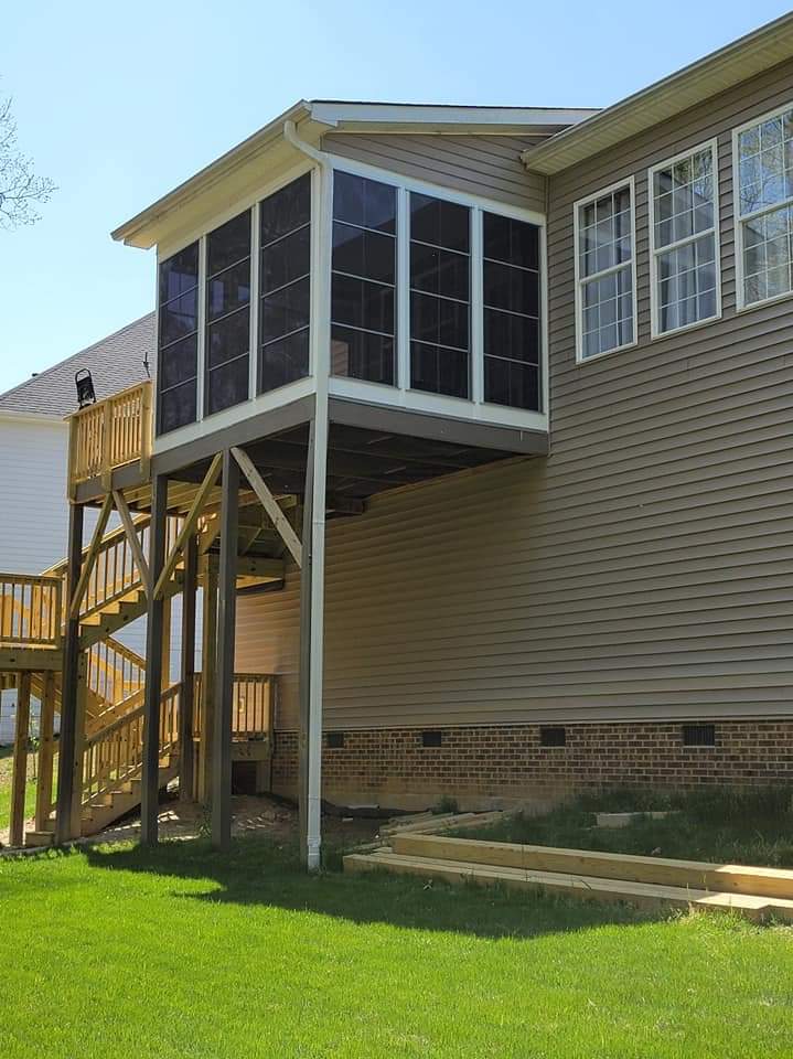 Screened-in porch on elevated platform with wooden stairs and green lawn.
