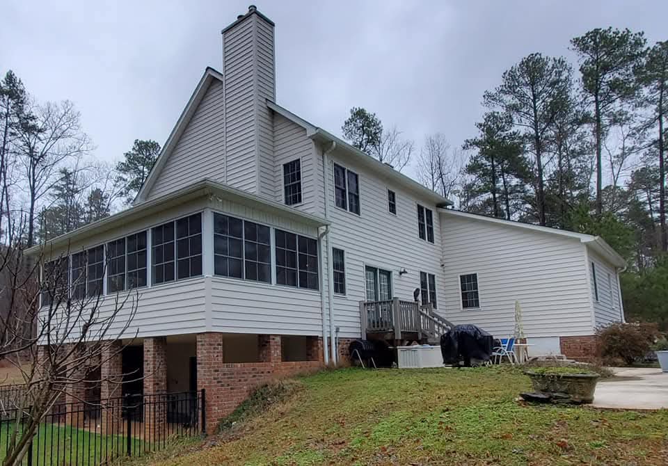 Two-story house with a screened porch, surrounded by trees and a grassy yard.