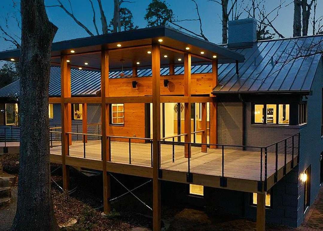 Modern home exterior at dusk featuring a wooden deck and sleek architectural design.