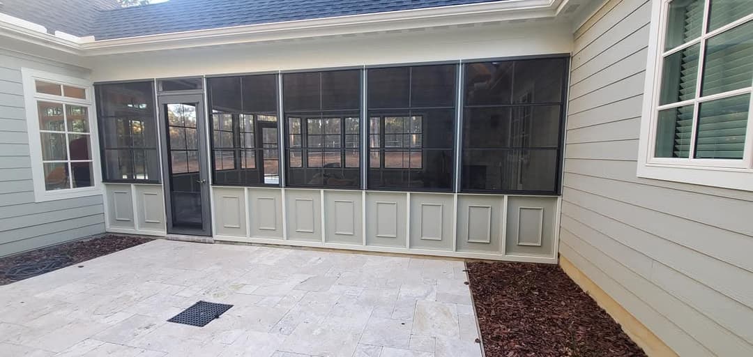 Modern glass-enclosed porch with gray walls and stone flooring, perfect for outdoor relaxation.