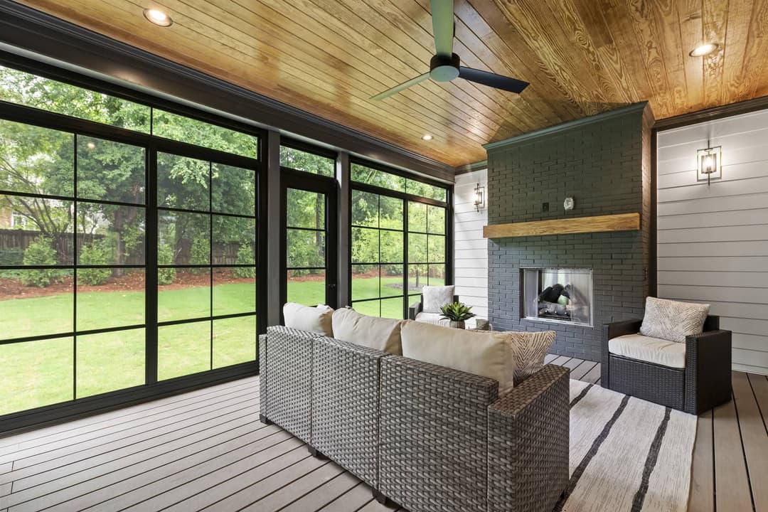 Stylish outdoor living space with a cozy sofa, modern fireplace, and large windows.