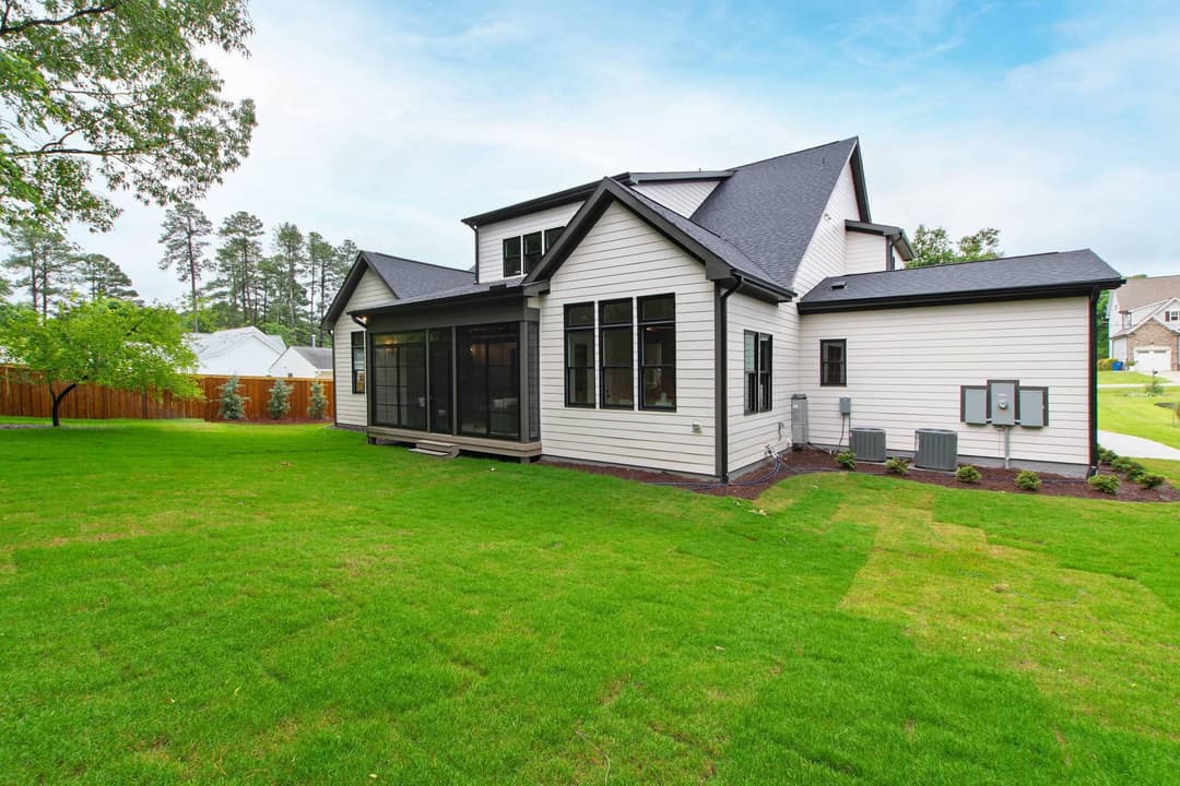 Modern two-story home with a screened porch and landscaped backyard in a serene setting.