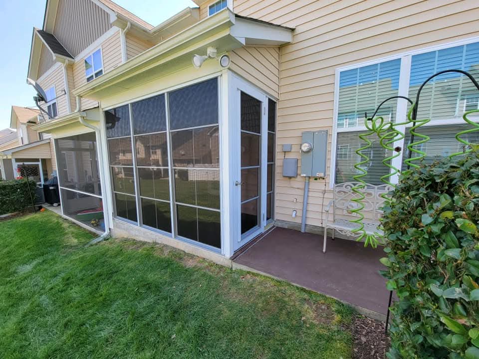 Screened porch with landscaped yard and residential building in the background.