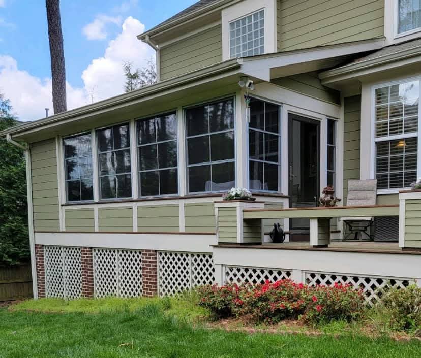Modern home exterior with a screened porch, green siding, and landscaped garden.