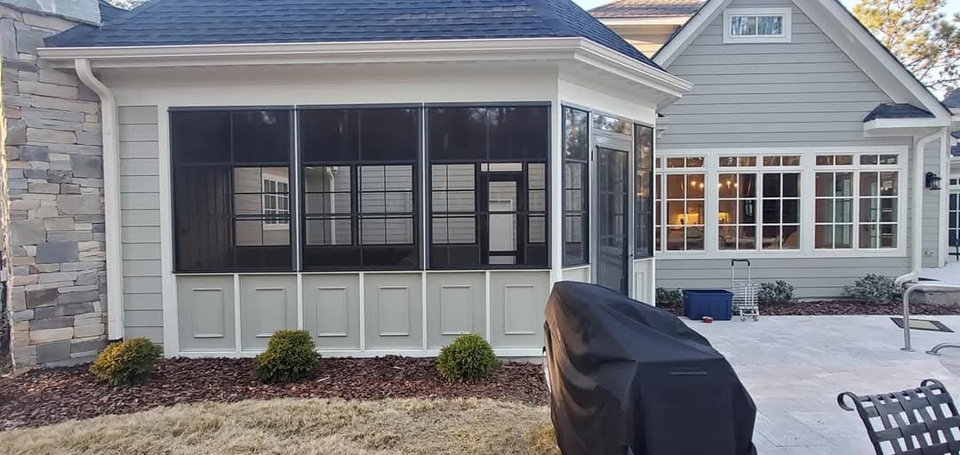 Modern screened-in porch with stone accents and patio furniture, enhancing outdoor living space.