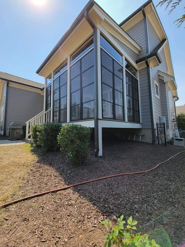 Modern home exterior featuring a screened porch and landscaped yard. Bright sunny day.