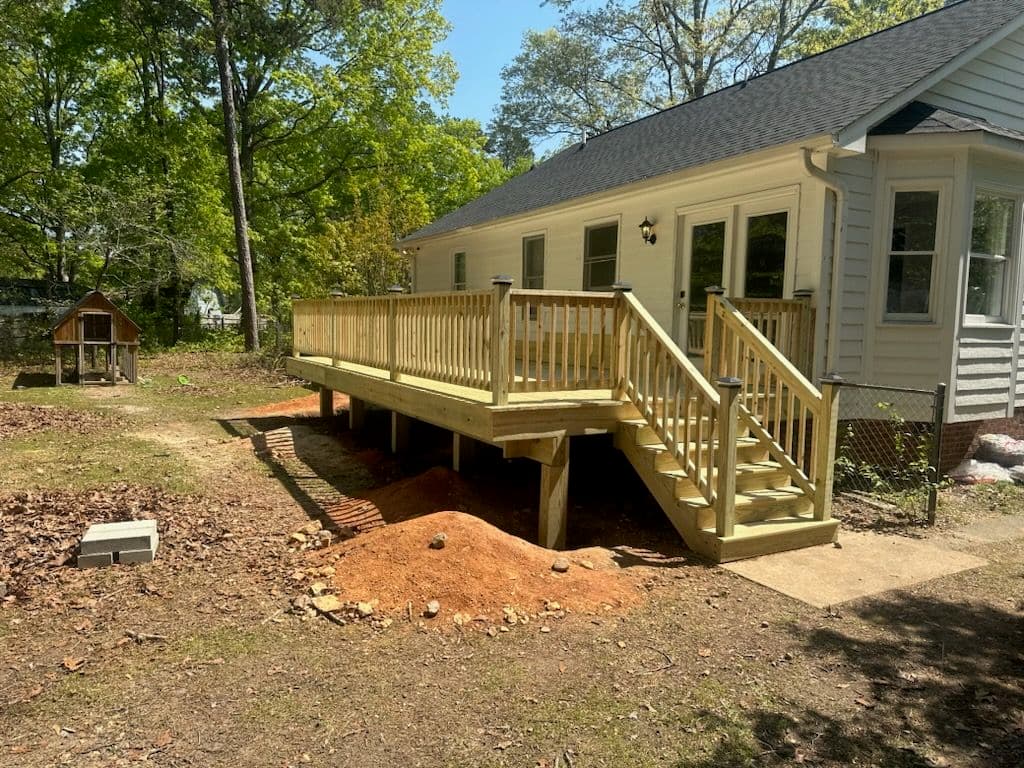 New wooden wheelchair-accessible deck provides easy access to a home in a landscaped yard.