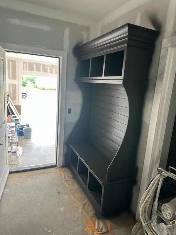 Modern dark wood cabinet with open shelving in an unfinished room.