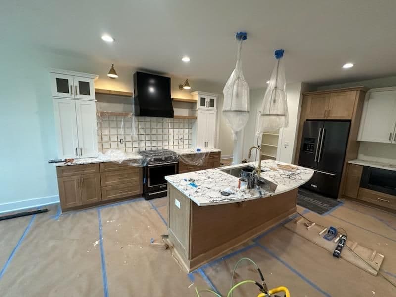 Modern kitchen renovation with granite countertops, an island, and updated cabinetry under construction.