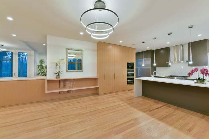 Modern kitchen with wooden cabinets, quartz countertops, and stylish overhead lighting.