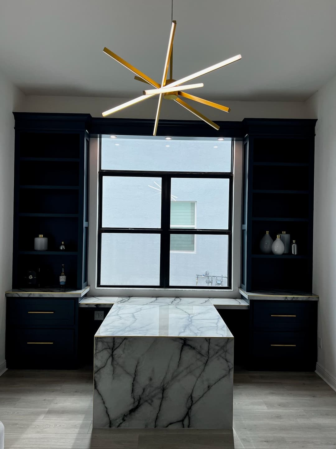 Modern kitchen design featuring a marble island, navy blue cabinets, and a stylish star pendant light.