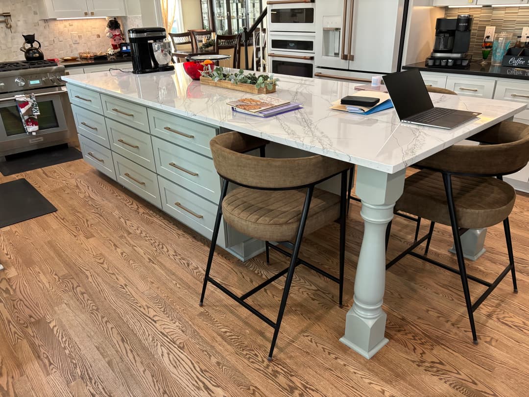 Modern kitchen with marble island, two bar stools, and sleek cabinetry for a stylish design.