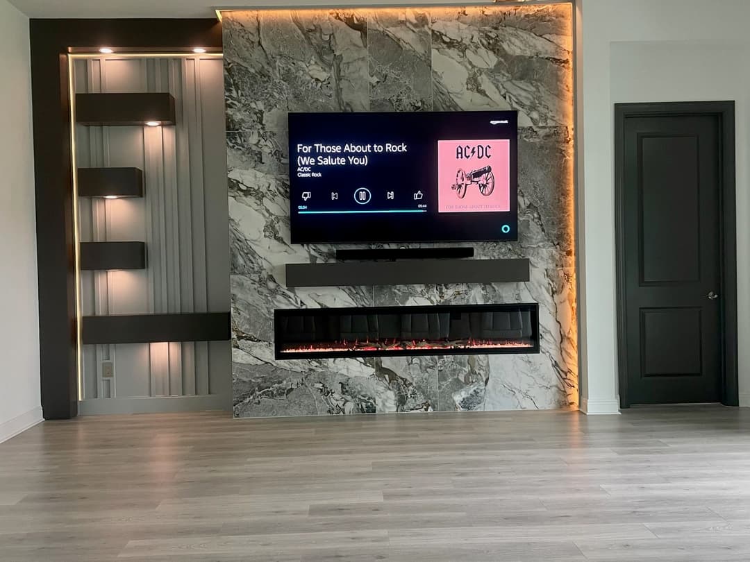 Modern living room with marble wall, TV displaying AC/DC album, and electric fireplace below.