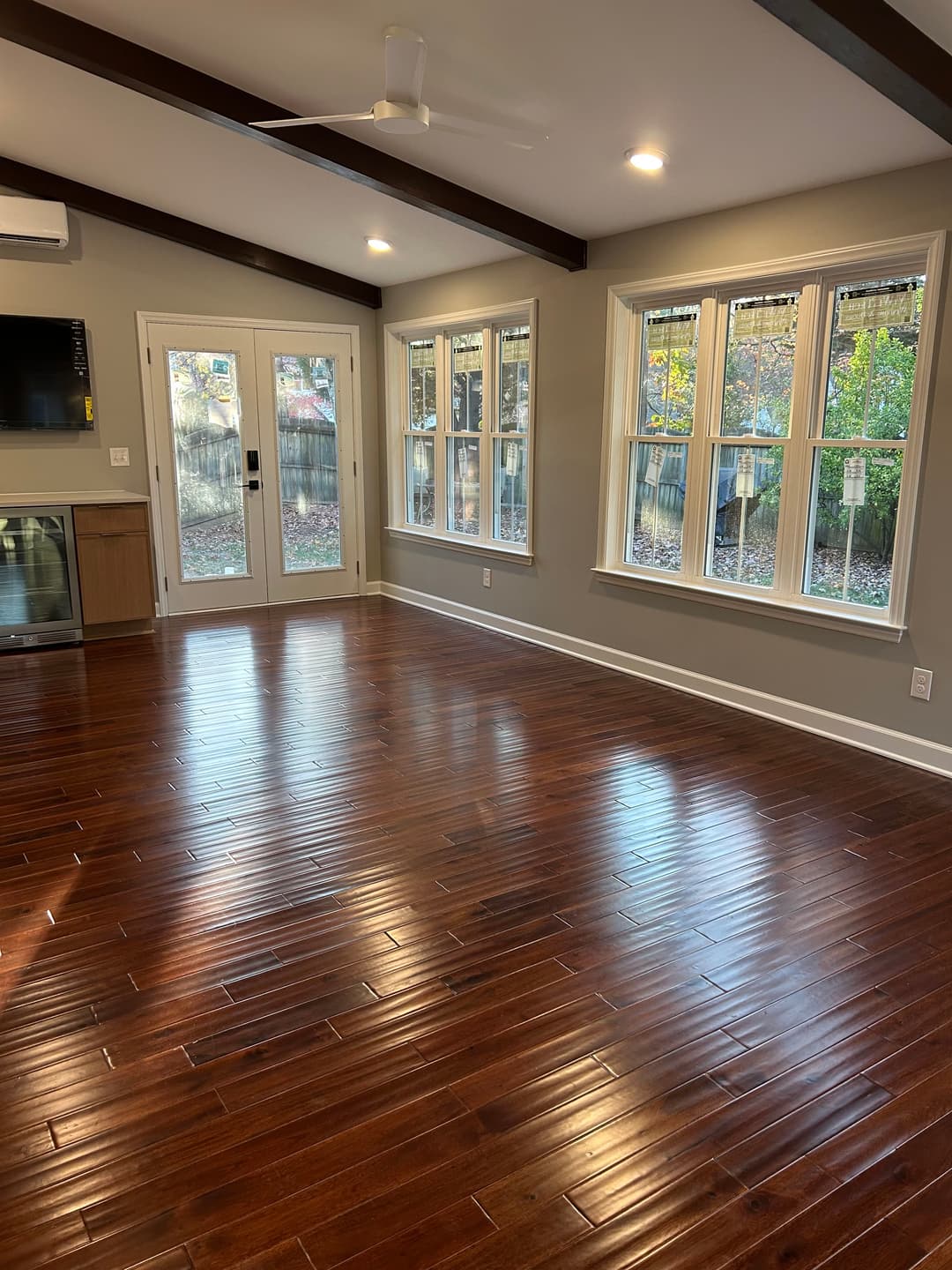 Spacious living room with hardwood floors, large windows, and natural light.
