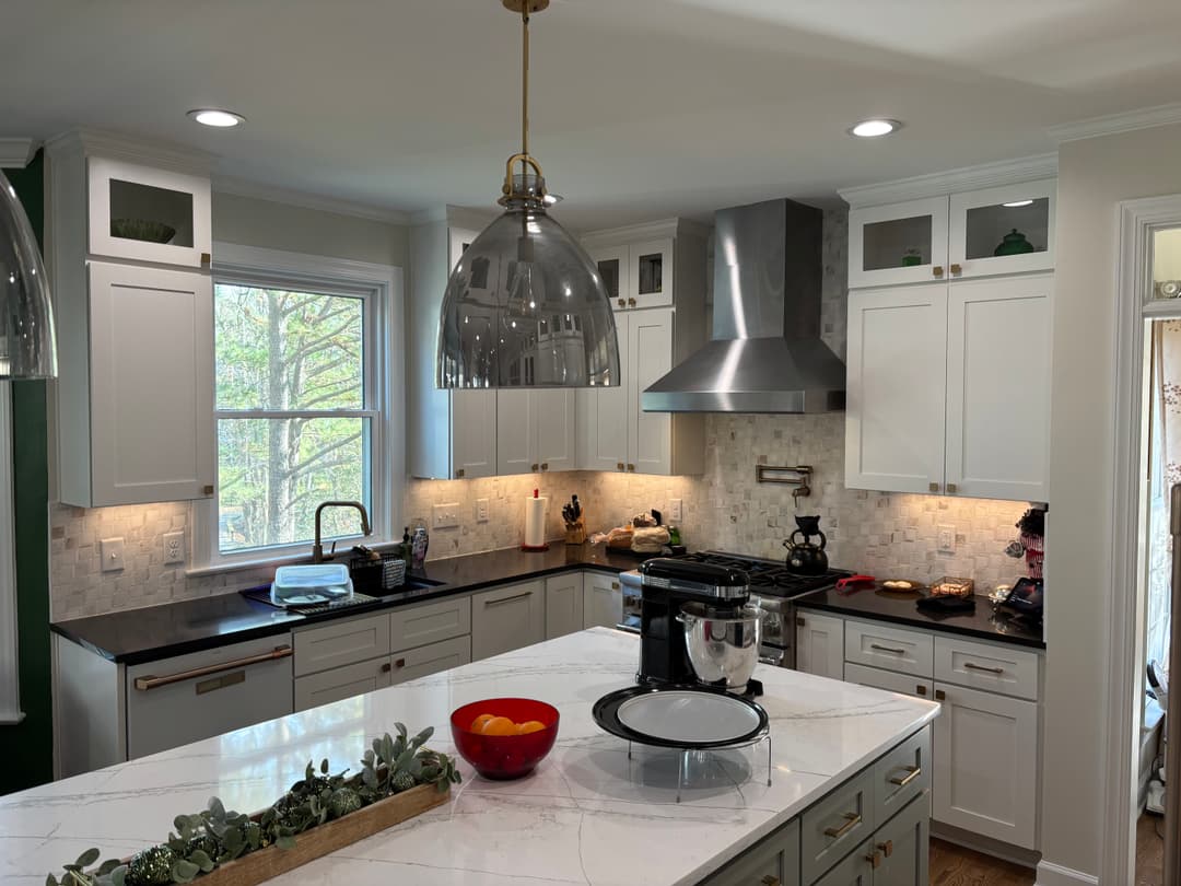 Modern kitchen with white cabinetry, quartz countertop, and pendant lighting over an island.